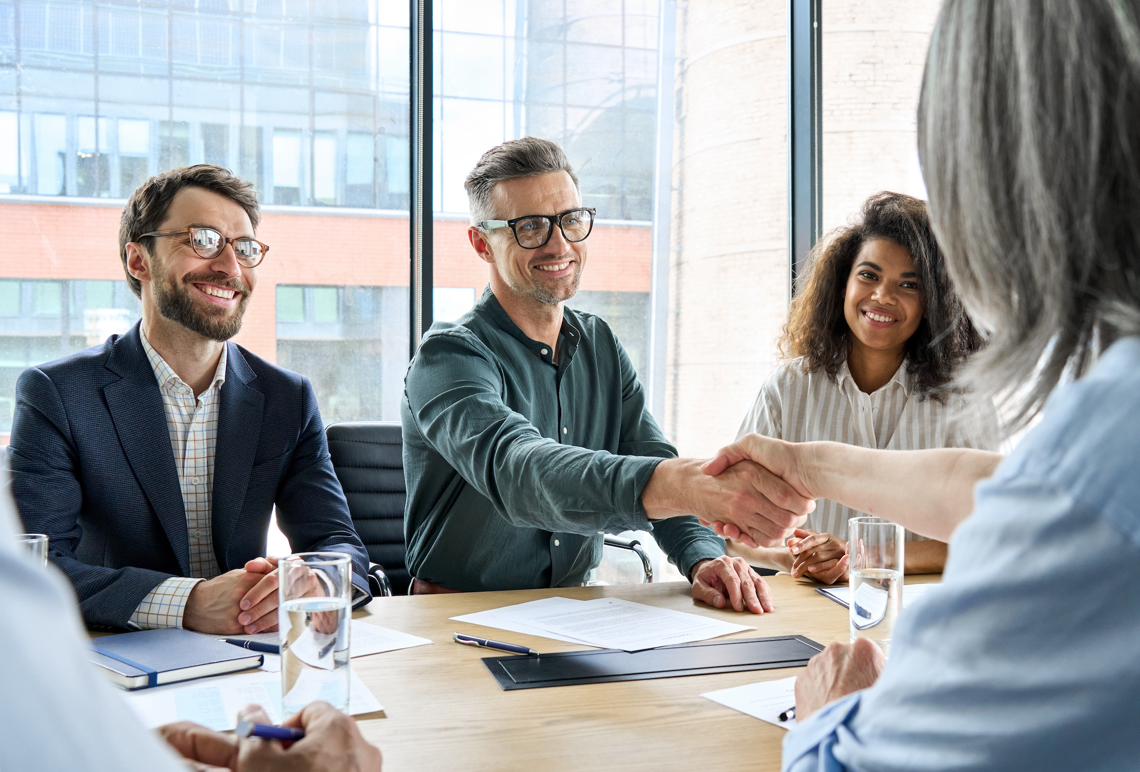 Happy businessman and businesswoman shaking hands at group meeting. The Key Role of Consumer Goods Headhunters in Building an Industry-Leading Team