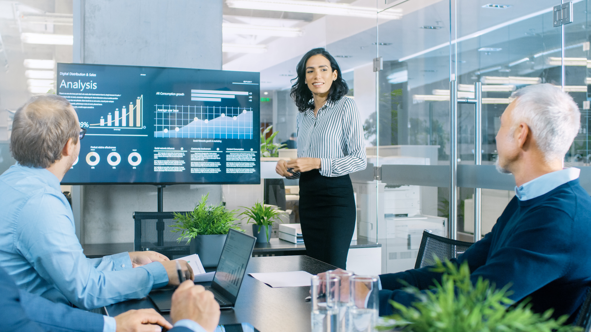 Chief Female Executive Gives a Report/ Presentation to Her Colleagues in the Meeting Room, She Shows Graphics, Pie Charts and Company’s Growth on the Wall TV. Building a Top-Tier Executive Consumer Goods Sales Team: A Guide by Hunter & Michaels