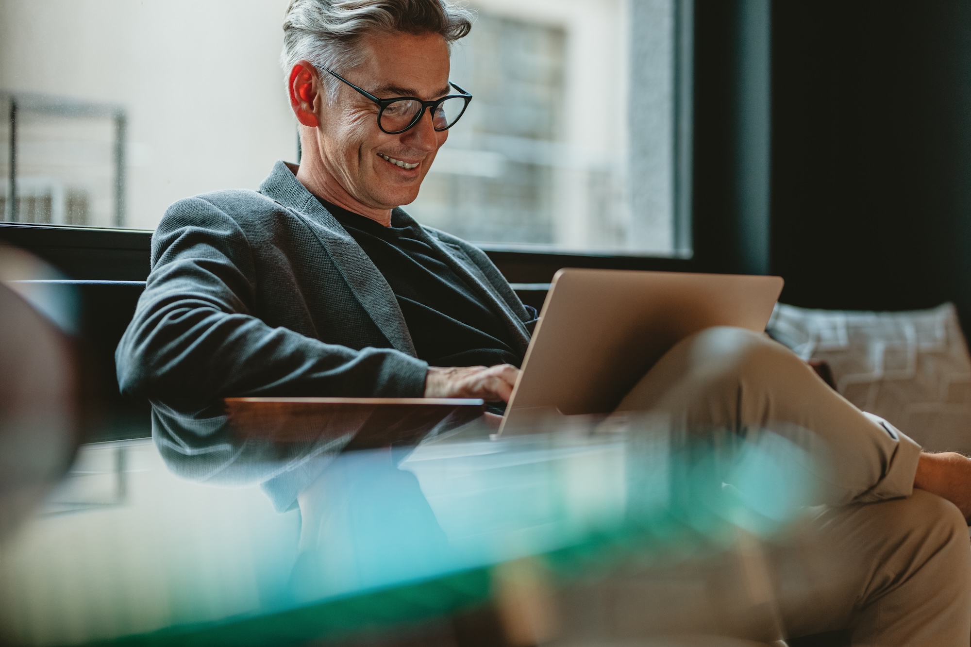Business professional working on laptop in office lobby How a CPG Agency Like Hunter & Michaels Transforms Executive Recruitment in the Consumer Packaged Goods Industry
