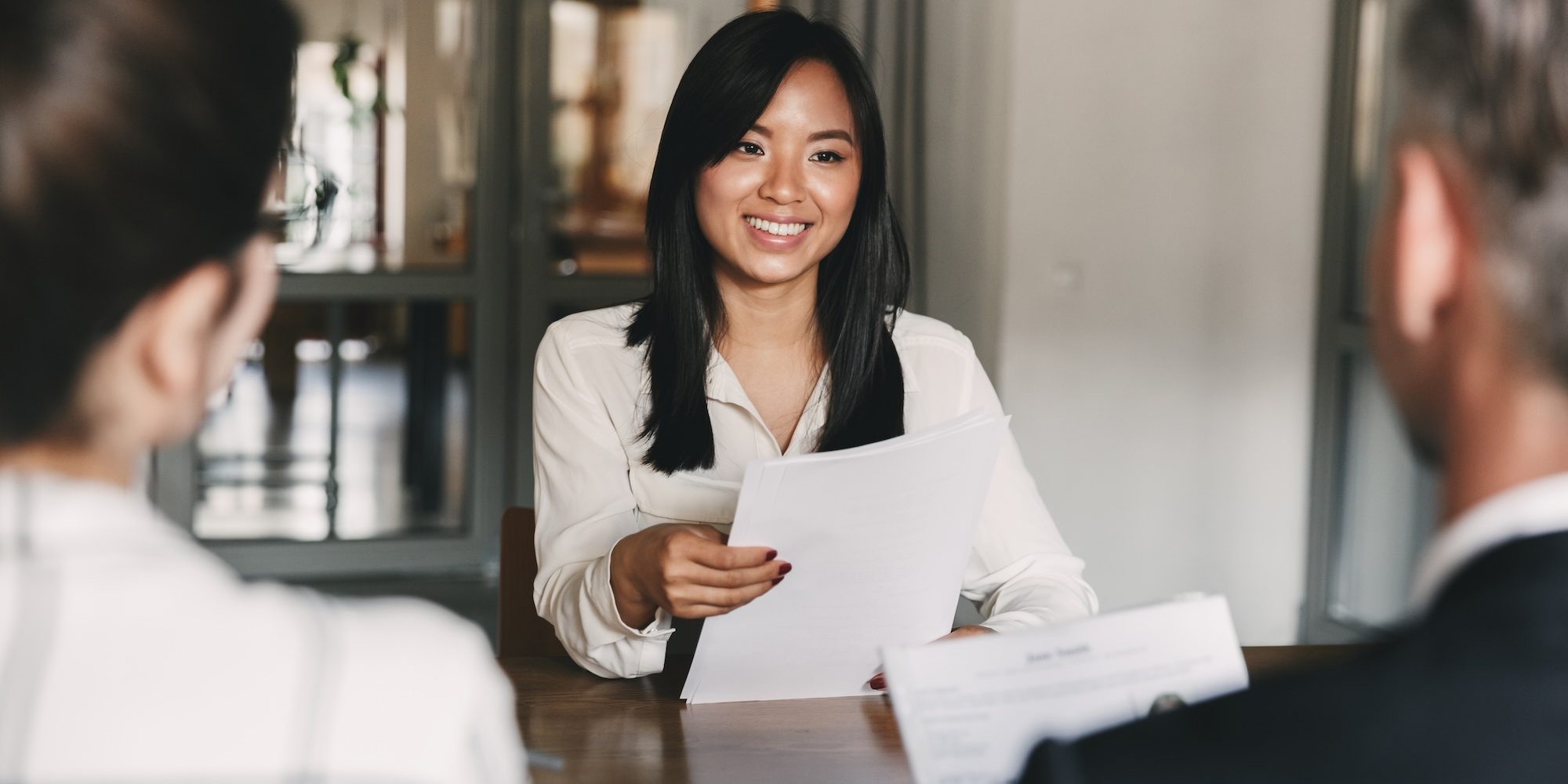 Business, career and recruitment concept – young asian woman smiling and holding resume, while interviewing as candidate for job in big company How to Attract Top Talent for Your CPG CFO Position: Expert Tips from Hunter & Michaels