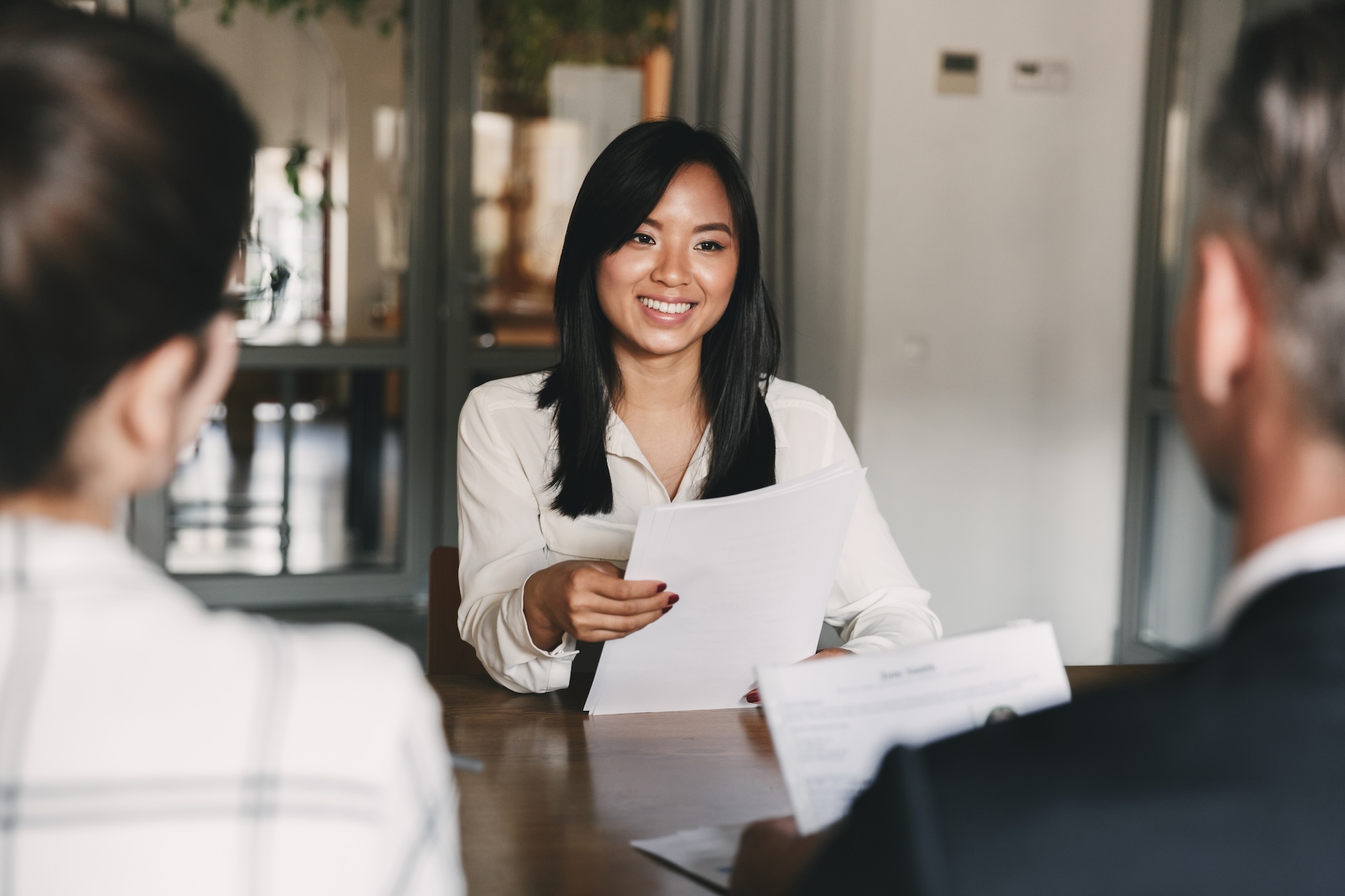 Business, career and recruitment concept – young asian woman smiling and holding resume, while interviewing as candidate for job in big company How to Attract Top Talent for Your CPG CFO Position: Expert Tips from Hunter & Michaels