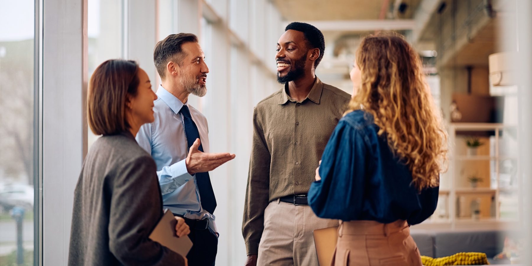 Happy multiracial business team talking in the office. The CPG COO Skill Set Has Changed. Has Your Recruiting Process Caught Up?